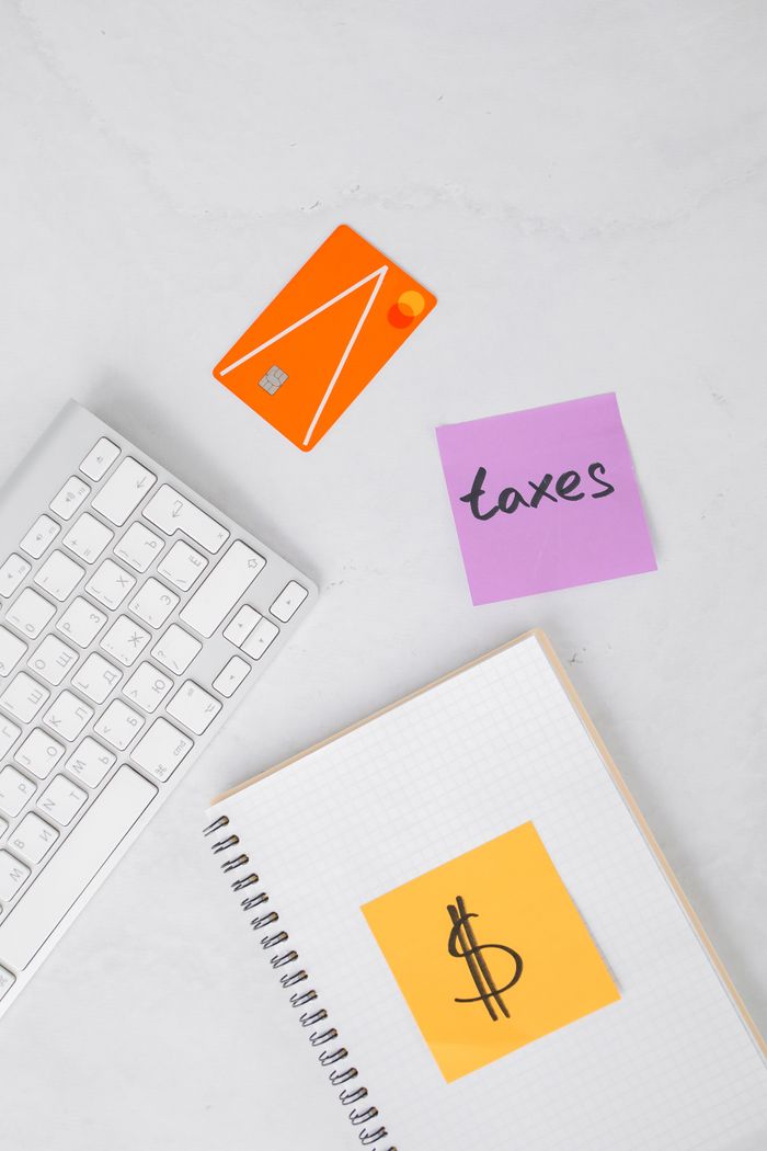 Flat lay of a financial workspace including a keyboard, credit card, and tax notes on a white surface.