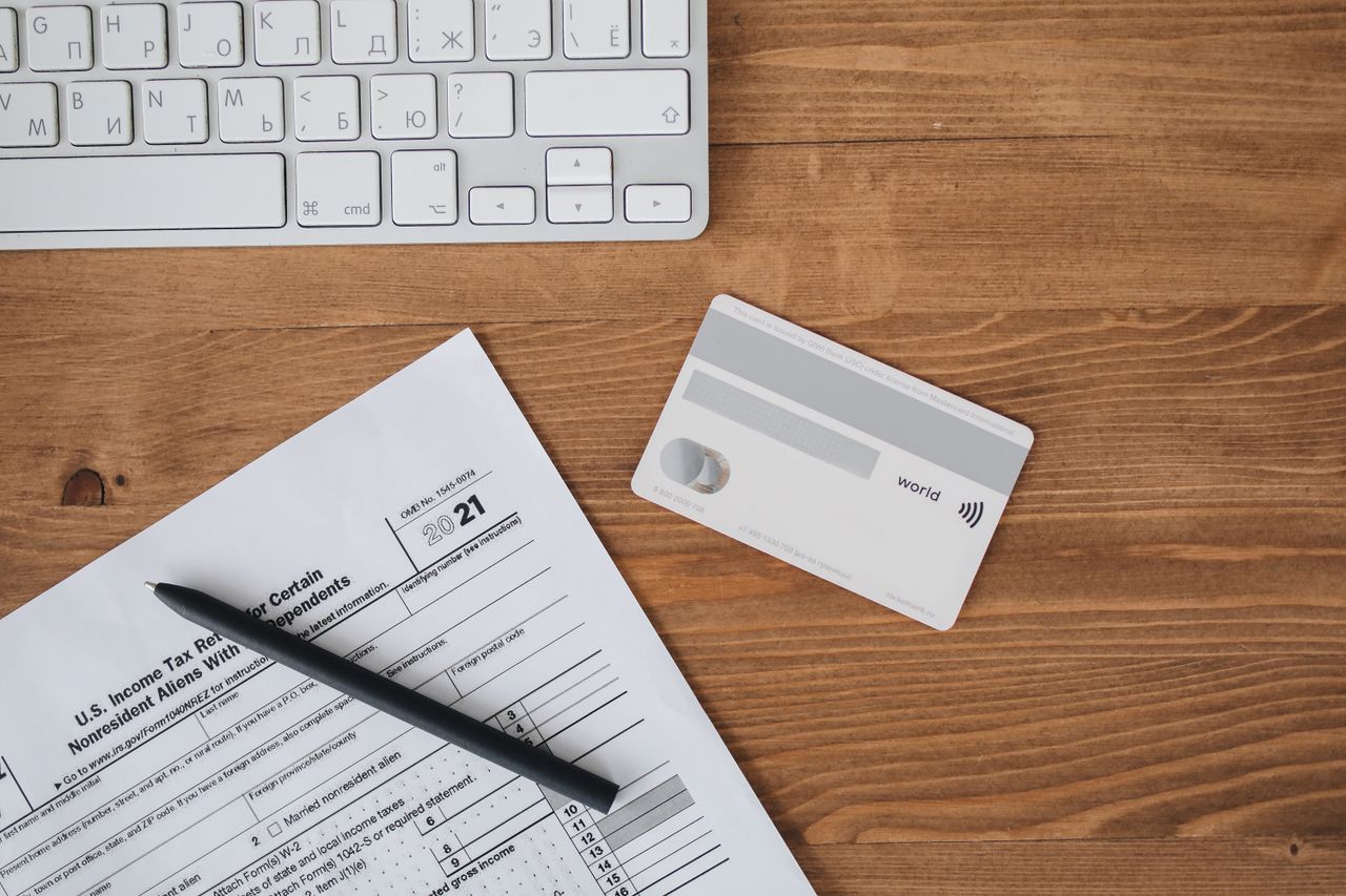 Overhead view of a desk with tax form, pen, keyboard, and contactless card.